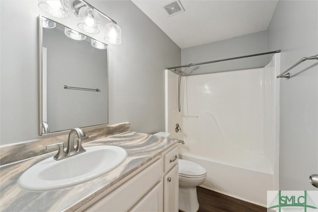 bathroom featuring visible vents, toilet, shower / tub combination, wood finished floors, and vanity