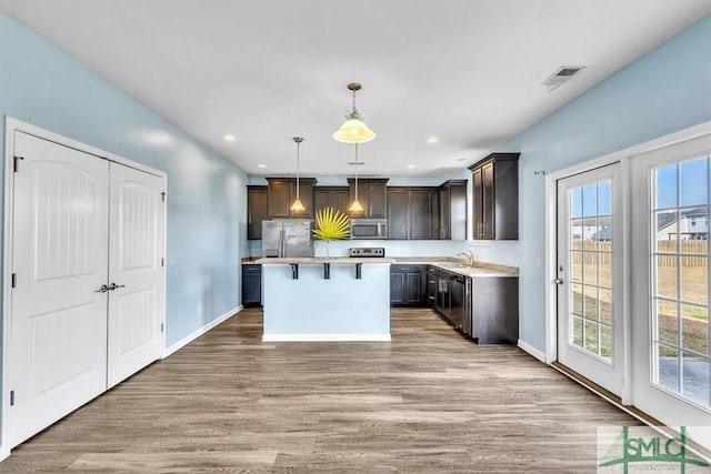 kitchen featuring dark brown cabinetry, a center island, a sink, light wood-style flooring, and stainless steel appliances