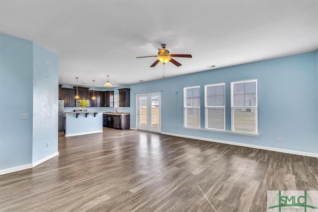 unfurnished living room featuring baseboards, a ceiling fan, and dark wood-style flooring