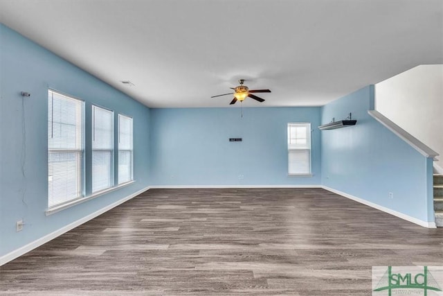 unfurnished living room featuring stairway, baseboards, a ceiling fan, and wood finished floors