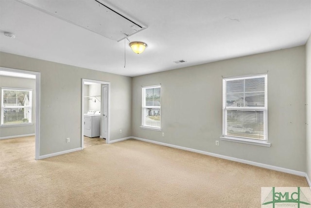 unfurnished bedroom featuring baseboards, light carpet, attic access, and washing machine and clothes dryer