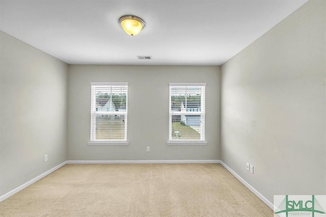 spare room featuring baseboards, light carpet, and visible vents