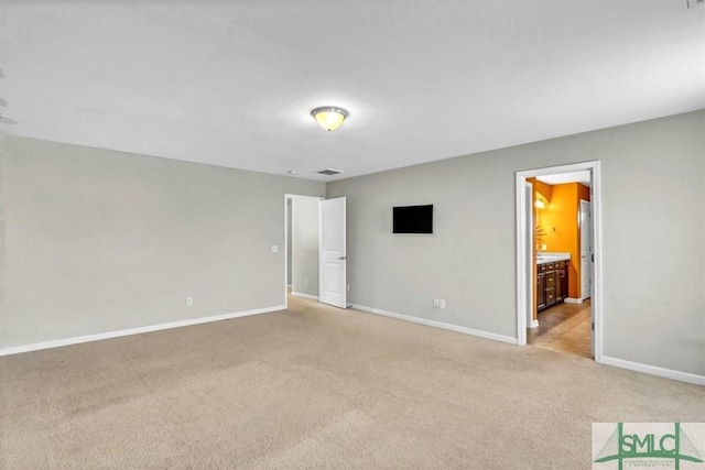 unfurnished bedroom with carpet floors, baseboards, and ensuite bath
