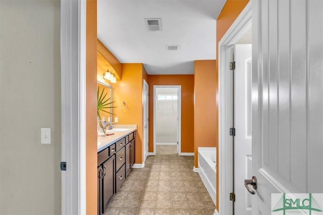bathroom with visible vents, a sink, a bath, and double vanity