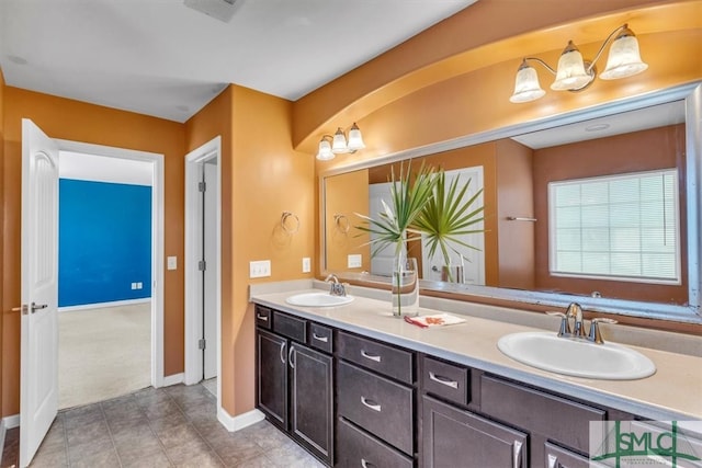bathroom featuring a sink, baseboards, double vanity, and visible vents
