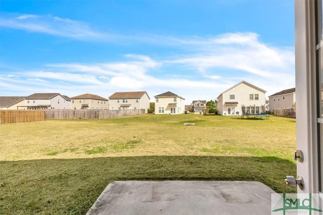 view of yard featuring a trampoline, a patio area, fence, and a residential view