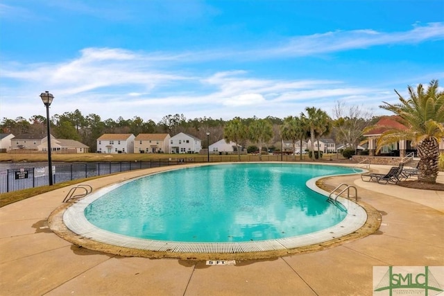 community pool featuring a patio area, fence, and a residential view
