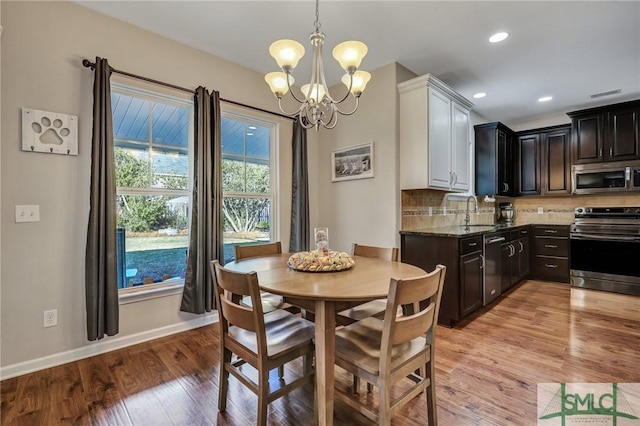 dining area featuring light wood-style floors, baseboards, a chandelier, and recessed lighting