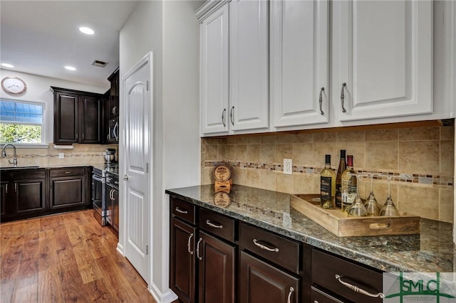 kitchen with dark brown cabinetry, appliances with stainless steel finishes, white cabinetry, and a sink