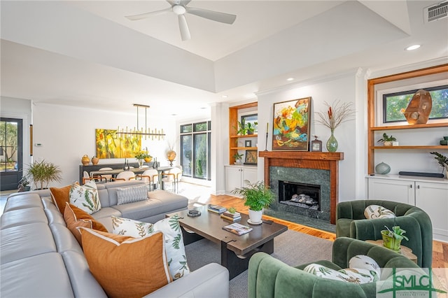 living area with built in features, wood finished floors, visible vents, and a healthy amount of sunlight