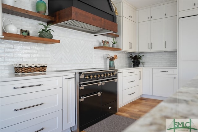 kitchen with range with two ovens, decorative backsplash, light countertops, premium range hood, and open shelves