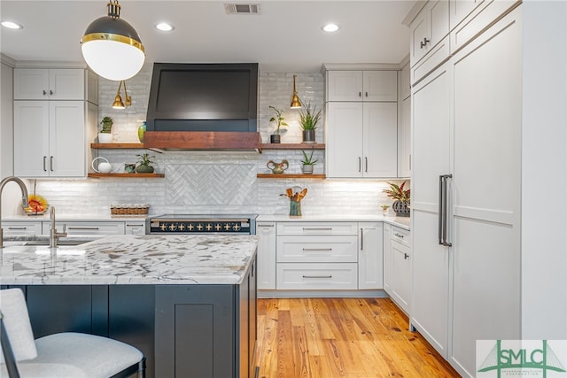 kitchen with wall chimney exhaust hood, stove, open shelves, and built in fridge