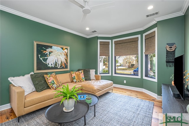 living area with visible vents, crown molding, baseboards, and wood finished floors