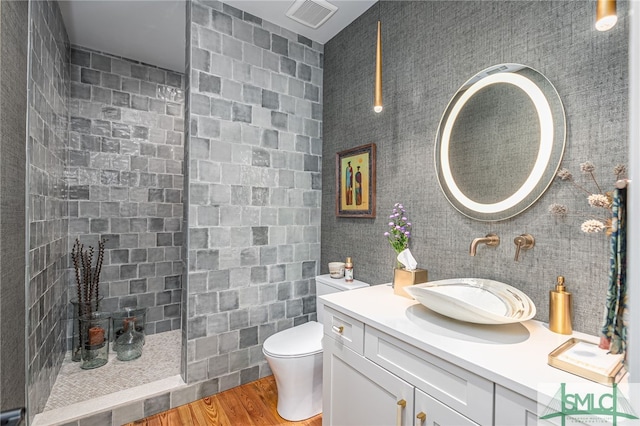 full bathroom featuring visible vents, toilet, wood finished floors, vanity, and a walk in shower