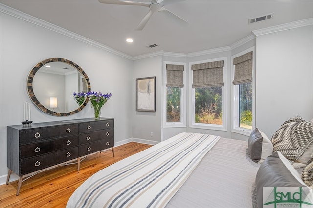 bedroom with baseboards, crown molding, visible vents, and wood finished floors