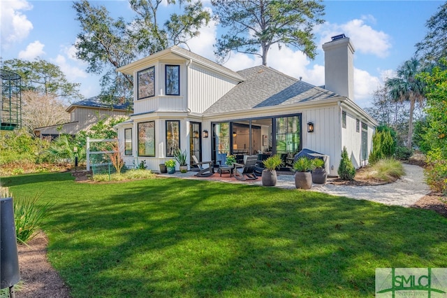 rear view of house featuring a patio, a yard, a chimney, and roof with shingles