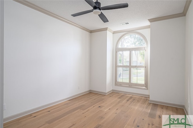 spare room with light wood finished floors, visible vents, ornamental molding, a textured ceiling, and baseboards