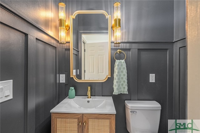 bathroom with vanity, toilet, and a decorative wall