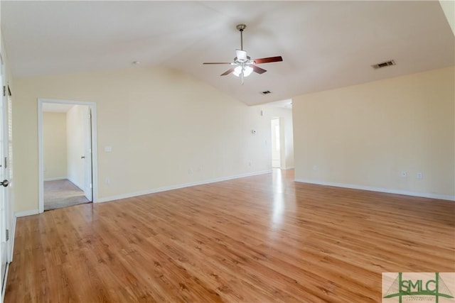 spare room featuring light wood-style flooring, visible vents, baseboards, vaulted ceiling, and a ceiling fan