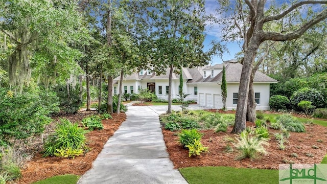 view of front of home with concrete driveway, an attached garage, and stucco siding