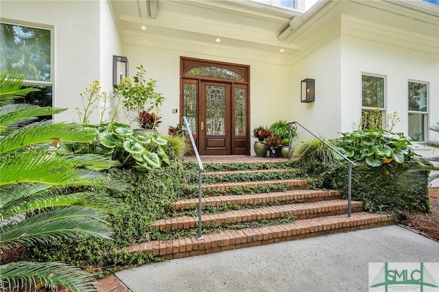 view of exterior entry featuring french doors, covered porch, and stucco siding