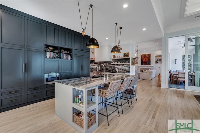 kitchen featuring open shelves, ornamental molding, light wood-style floors, light stone countertops, and a kitchen bar