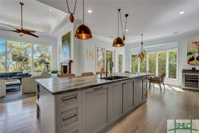 kitchen with wine cooler, a sink, open floor plan, ornamental molding, and a wealth of natural light