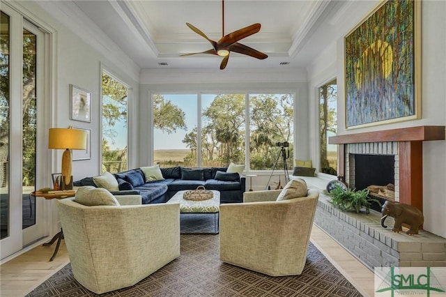 sunroom / solarium with a ceiling fan, a raised ceiling, and a fireplace