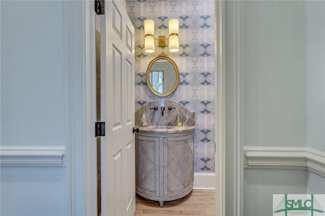 bathroom featuring wood finished floors and wallpapered walls