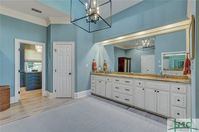 bathroom with crown molding, double vanity, a sink, wood finished floors, and baseboards