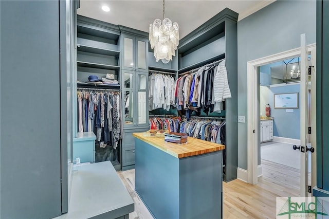 walk in closet featuring light wood-style floors and a notable chandelier