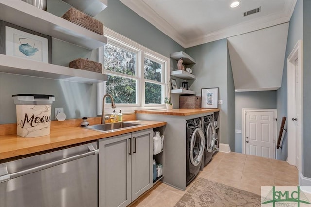 laundry area with light tile patterned floors, visible vents, washer and clothes dryer, ornamental molding, and a sink