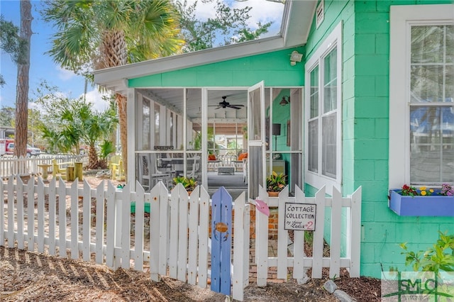 exterior space featuring a sunroom, concrete block siding, fence, and ceiling fan