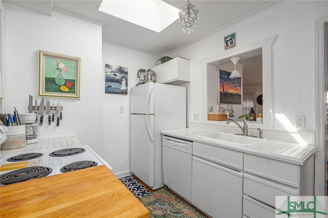 kitchen featuring white appliances, a skylight, a sink, white cabinets, and crown molding