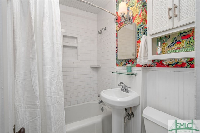 bathroom featuring shower / tub combo, wainscoting, and toilet