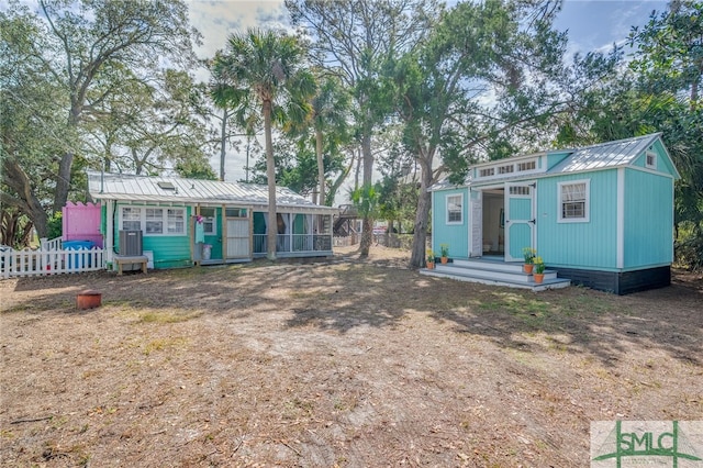 view of front of home with an outbuilding, metal roof, and fence