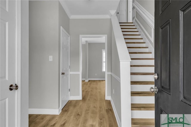 entrance foyer featuring ornamental molding, light wood finished floors, stairway, and baseboards