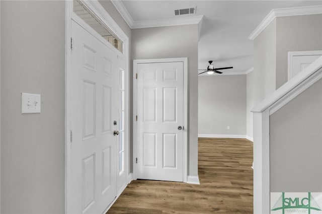 foyer featuring baseboards, visible vents, crown molding, and wood finished floors