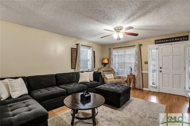 living room featuring ceiling fan, a textured ceiling, and wood finished floors