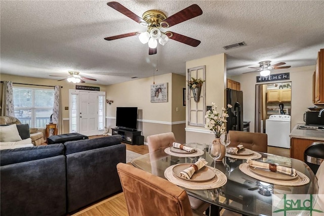 dining area with light wood-type flooring, washer / dryer, visible vents, and a textured ceiling