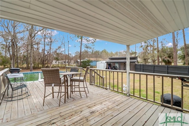 wooden deck with a lawn, a storage shed, fence, an outdoor pool, and an outdoor structure