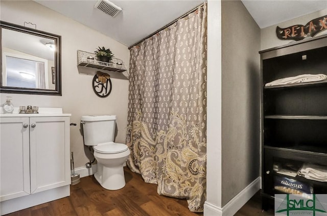 full bath with baseboards, visible vents, toilet, wood finished floors, and vanity