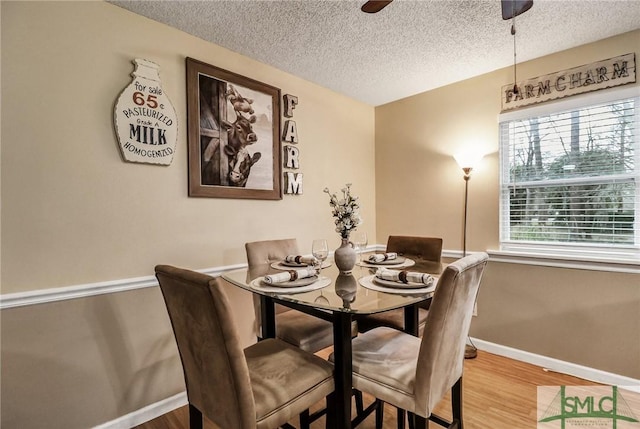 dining area with a ceiling fan, a textured ceiling, baseboards, and wood finished floors