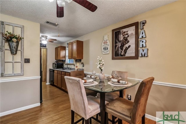 dining area featuring visible vents, a ceiling fan, a textured ceiling, wood finished floors, and baseboards