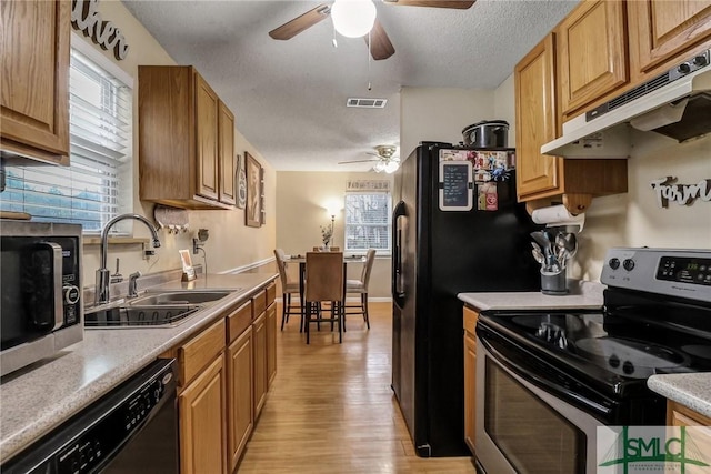 kitchen featuring under cabinet range hood, stainless steel appliances, a sink, visible vents, and light wood-type flooring