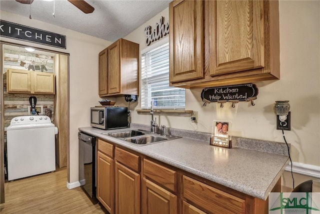 kitchen with a sink, black dishwasher, brown cabinets, stainless steel microwave, and washer / dryer