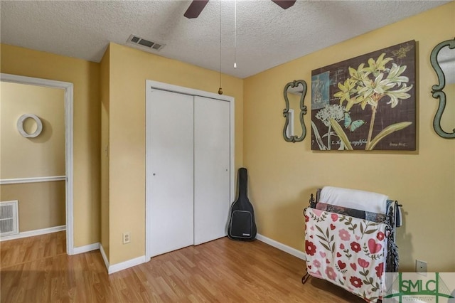 sitting room with baseboards, a textured ceiling, visible vents, and wood finished floors