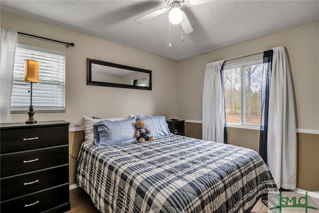 bedroom with baseboards, a ceiling fan, dark wood finished floors, and a textured ceiling