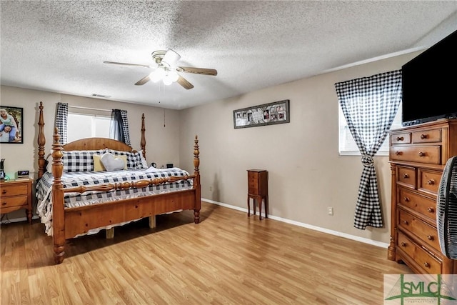 bedroom with a textured ceiling, ceiling fan, light wood-style flooring, and baseboards