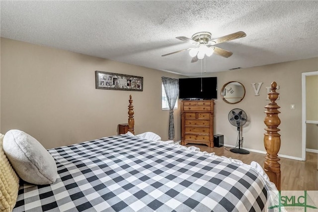 bedroom with baseboards, visible vents, a ceiling fan, wood finished floors, and a textured ceiling